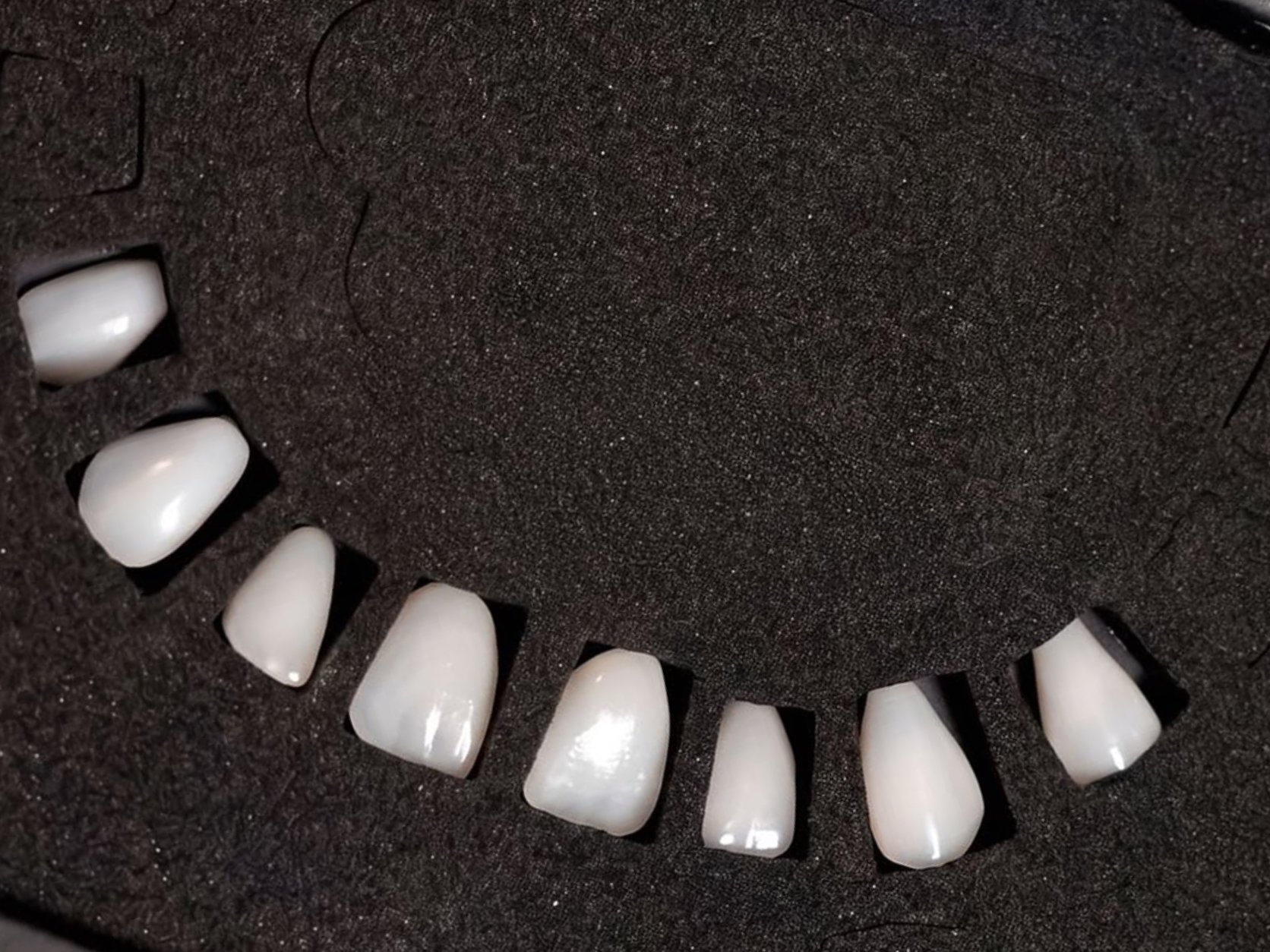 Dental veneers held in precision-cut black foam cavities