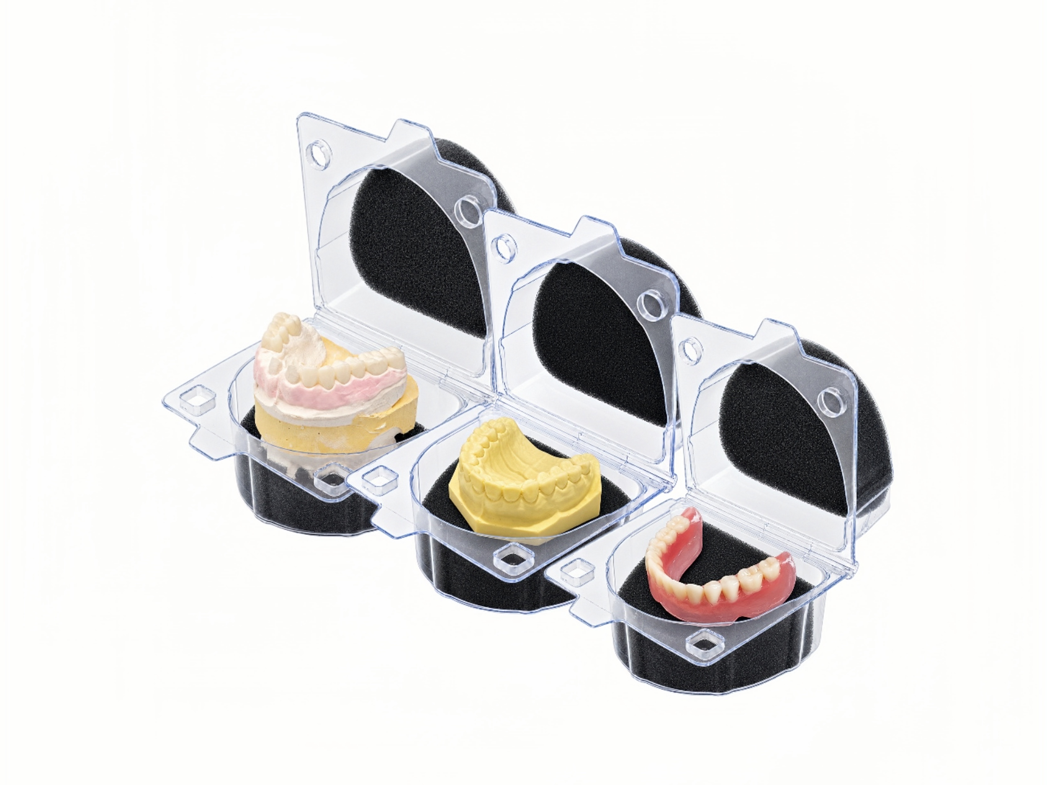 Three open foam-lined shipping boxes holding dental models and a denture